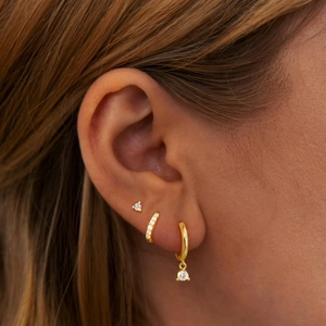 Detailed view of three-piece 14K gold zircon earrings set worn on a model's ear