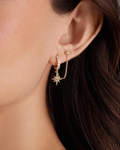 Macro view of 14K gold plated sun star chain earrings with zircon on a model's ear