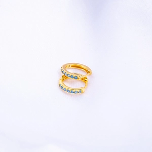 Close-up of gold-plated hoop earrings featuring elegant micro-set blue cubic zirconia stones