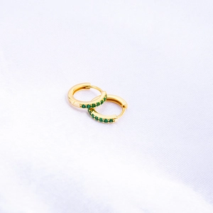 Detail view of gold S925 sterling silver huggie earrings with inlaid green zircon stones
