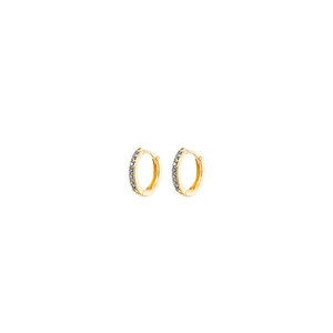 Macro detail of gold huggie earrings featuring micro-paved round blue zircon stones