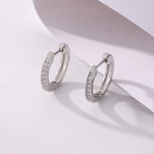 Detail view of silver huggie earrings featuring micro-pave cubic zirconia inlay stones