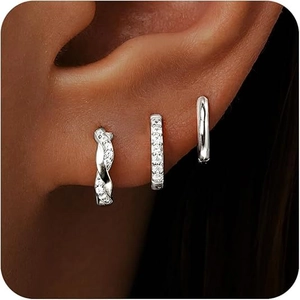 Close-up of three stacked silver earrings featuring cubic zirconia pavé and twisted designs