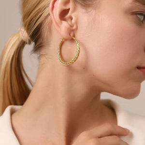 Elegant gold braided hoop earrings featuring a twisted rope texture on a model side view