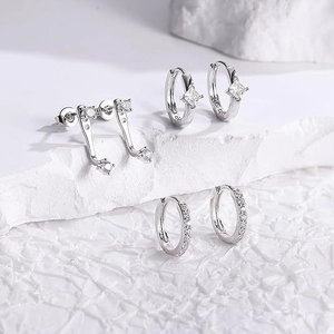 Dettaglio di set orecchini in argento S925 con zirconi e ciondoli a stella su pietra