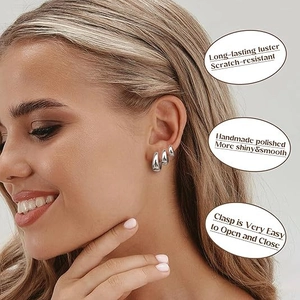 Close-up of three polished silver hoop earrings stacked on ear with secure clasp