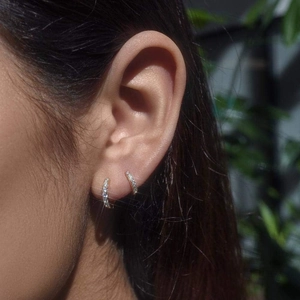 Close-up of sparkling 14K gold huggie earrings with micro-pave crystals on ear