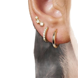 Close-up of gold ear cuff set with three-stone stud and pavé zircon hoop on ear