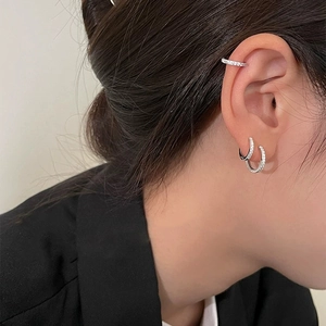 Primer plano de pendientes de aro y manguito de oreja en plata S925 con circonitas engastadas