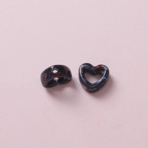 Macro shot of heart-shaped ceramic beads with red and white camouflage patterns for DIY crafts