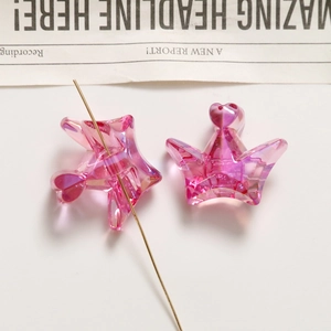Close-up of pink transparent heart and star beads with crown detail for DIY crafts