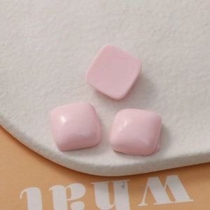 Macro shot of three 15mm pink macaron square resin charms for DIY jewelry and phone cases