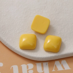 Macro detail of three glossy yellow square resin charms for DIY earring and phone case crafts