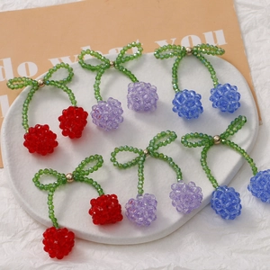 Macro view of handmade crystal cherry beads for hair clips in red, purple, and blue colors