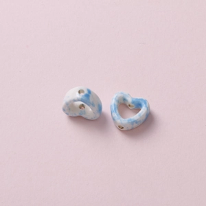 Close-up of heart-shaped ceramic beads with blue marble pattern and precision holes