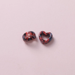 Macro shot of two heart-shaped ceramic beads with red and blue marble texture for DIY jewelry