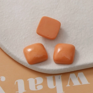 Close-up of three glossy orange resin square patches on a textured display tray