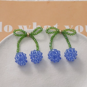 Detail of handmade beaded cherry hair clip with teal crystal beads and bow accent