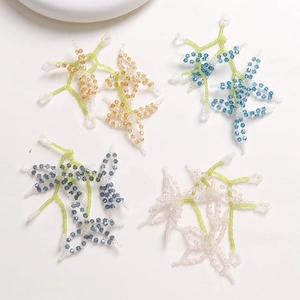 Macro detail of handmade beaded crystal flowers in amber, blue, and pink for DIY jewelry