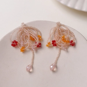 Macro detail of handmade beaded tassel earrings with crystal flowers and pink teardrop beads
