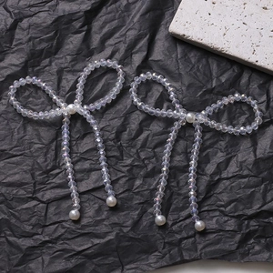 Close-up of handmade iridescent crystal bow with white pearls and long tassels