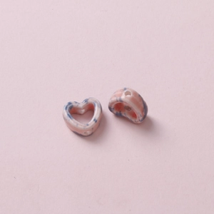 Macro detail of heart-shaped ceramic beads with pink and blue marbled pattern and side hole
