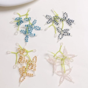 Close-up of handmade beaded flower charms in four colors for DIY jewelry making