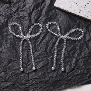 Detail of handcrafted bow earrings featuring iridescent crystal beads and white pearls