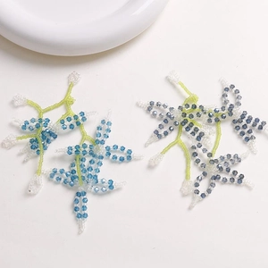 Detail of handmade beaded flower accessory with green and blue crystal beads