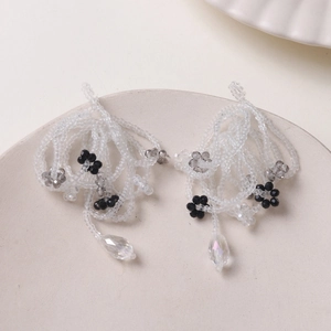 Macro detail of handmade beaded earrings with white floral petals and water-drop pendants