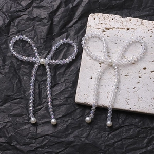 Detailed view of handmade bow charms with clear faceted beads and white faux pearls