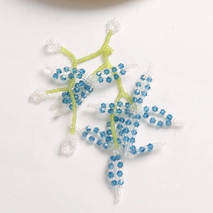 Detail of handmade beaded floral accessories with blue crystal beads and green seed beads