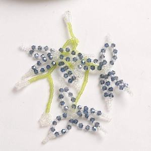 Detail of three handmade beaded flower patches with blue crystal and yellow beads