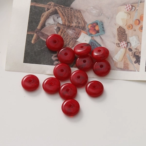 Gros plan de perles en résine rouge foncé avec texture marbrée noire et trou central
