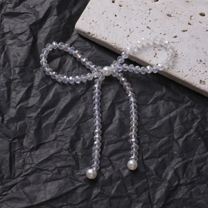 Elegant beaded bow ornament with iridescent crystal beads and white pearls on black texture