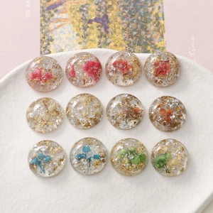 Detailed macro view of twelve resin flower charms with gold foil in a white ceramic dish