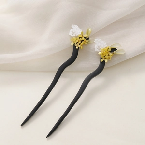 Detail of wooden hair sticks with yellow flowers, white jade rabbit, and green leaves
