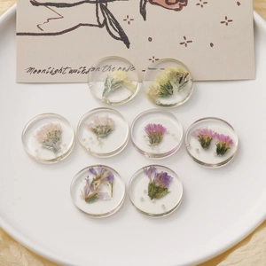 Detailed view of handmade clear resin round charms with real dried flowers and pearls