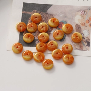 Détail de perles donuts en résine ambrée aux motifs marbrés de miel et crème