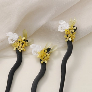 Macro detail of wooden hairpins with white rabbit, yellow flowers and leaves