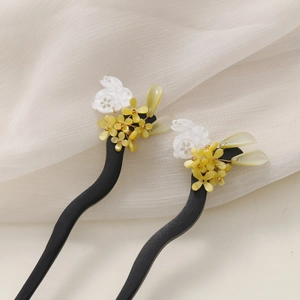 Detail of wooden hair sticks with carved rabbits, yellow flower clusters and green drops