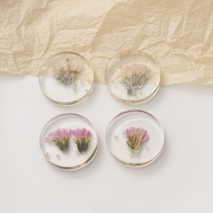 Top view of four handmade round resin earrings with dried flowers and tiny pearls