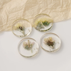 Flat lay of clear resin round pendants with dried flowers and pearls for DIY jewelry