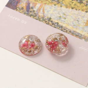 Close-up of resin round charm with red dried flowers, gold and silver foil inlays