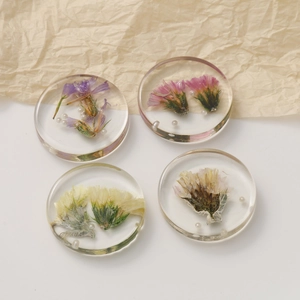 Macro detail of transparent resin charms with dried flowers and small pearls in 2x2 grid