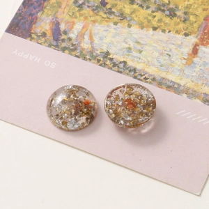 Macro shot of circular resin charm with gold and silver foils for DIY jewelry making