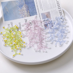 Handmade beaded flower tassel accessories in pastel colors displayed on a white tray