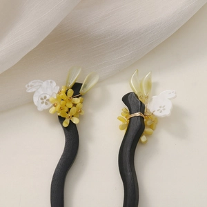Detailed close-up of handmade wooden hair sticks with floral and rabbit pendant charms