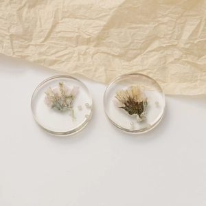 Detailed macro view of clear resin round pendant with dried pink flowers and small pearls