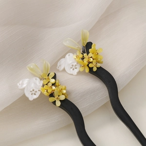 Detail of wooden hair sticks with yellow glass flower and white rabbit motif